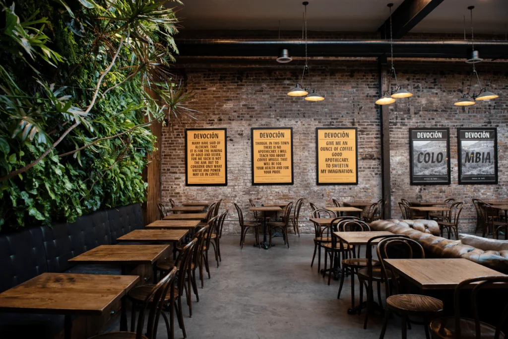 Devoción Coffee Shop in NYC with rustic exposed brick walls, wooden tables, and a striking living plant wall, offering a trendy and relaxed ambiance.
