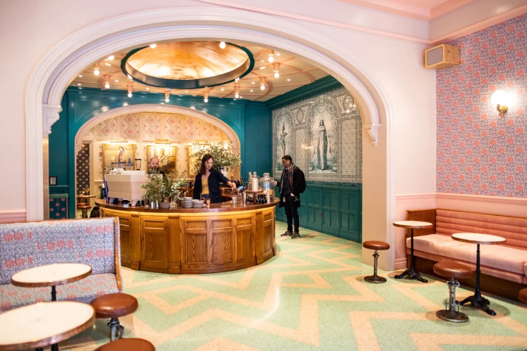 Felix Roasting Co. café interior in NYC with pastel decor, teal walls, and a central wooden coffee bar.