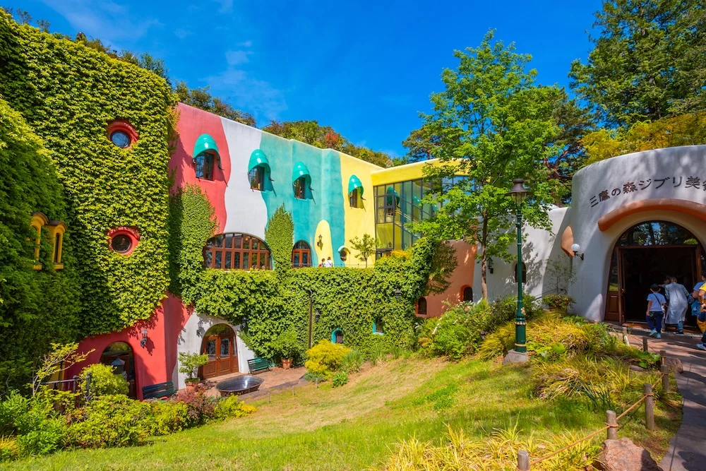 A whimsical entrance to the Ghibli Museum in Tokyo, featuring lush greenery and magical architecture.
