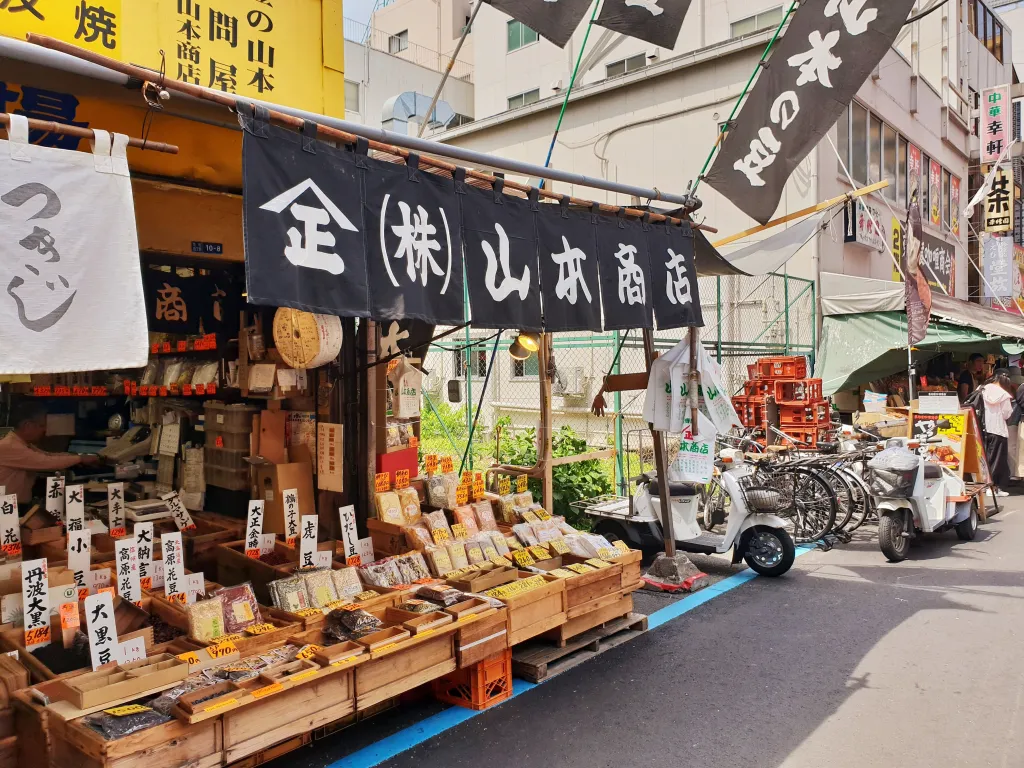 A lively food stall at Tsukiji Outer Market, selling fresh sushi and street snacks.