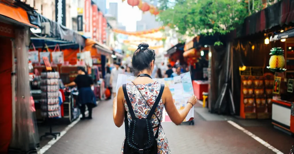 A solo traveler checking their phone for navigation while staying aware of their surroundings.