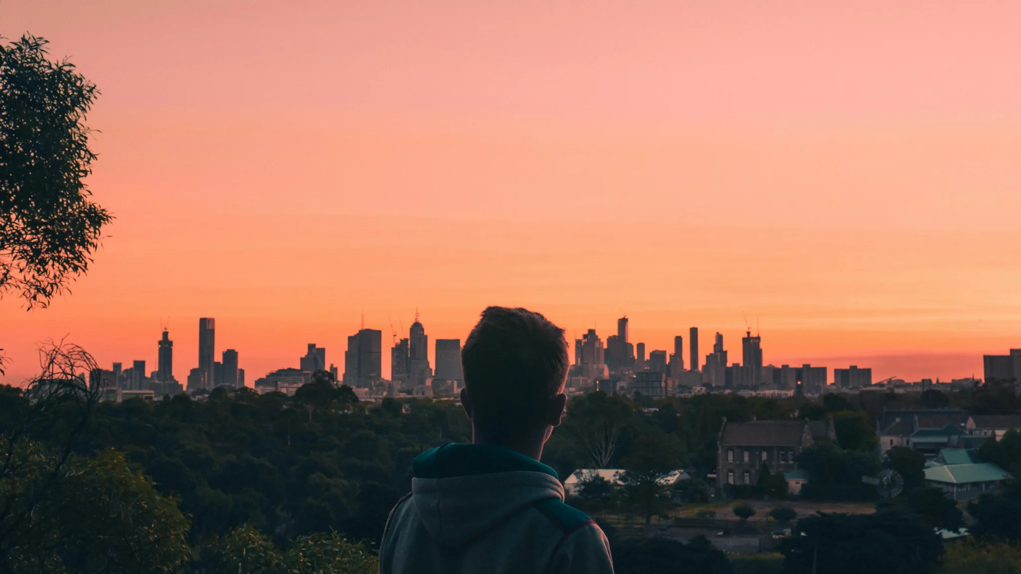 man standing with new york city's skyscappers in background at sunset.