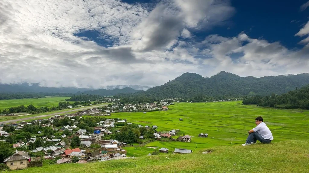 man sitting on a hill and looking at beautiful ziro valley